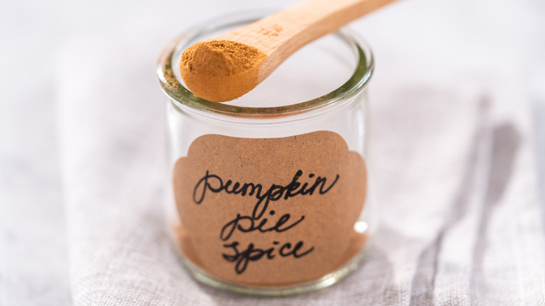 A glass that says pumpkin pie spice with a spoon on top