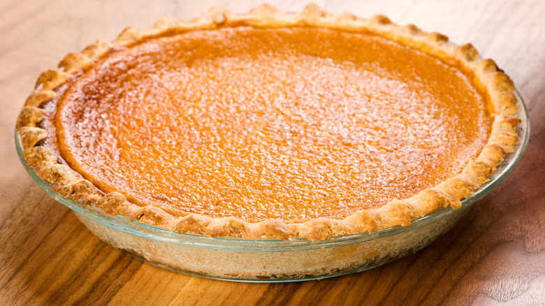 Close up of a whole sweet potato pie on a wooden table