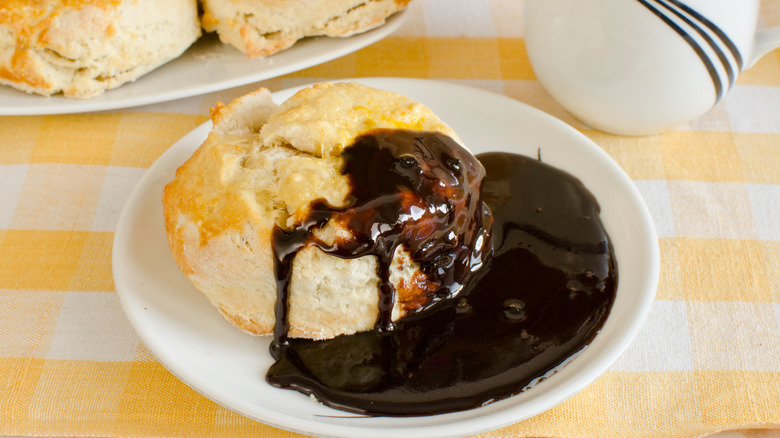 Close up of a biscuit topped with chocolate gravy against a white and yellow background