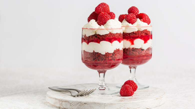 Two individual glasses of fruit trifle against a white background