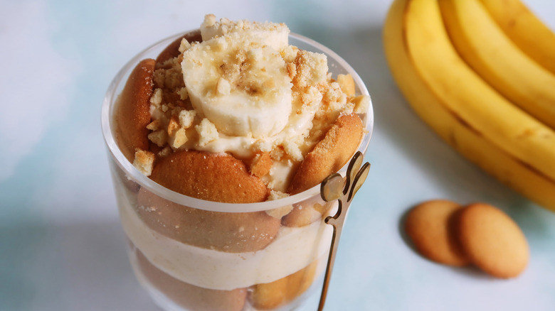 A cup of homemade banana pudding with vanilla wafers against a blue background