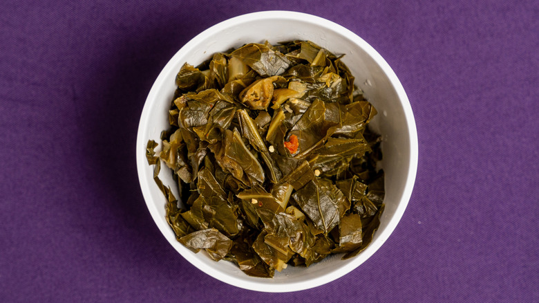 A bowl of collard greens against a purple background