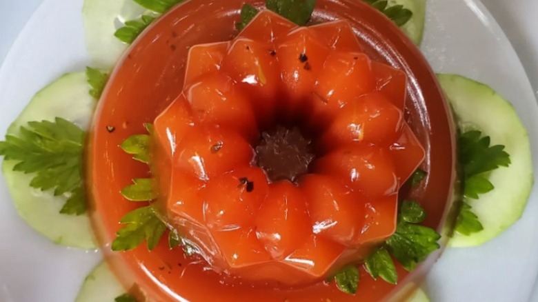 Tomato aspic arranged on green cucumbers with greenery