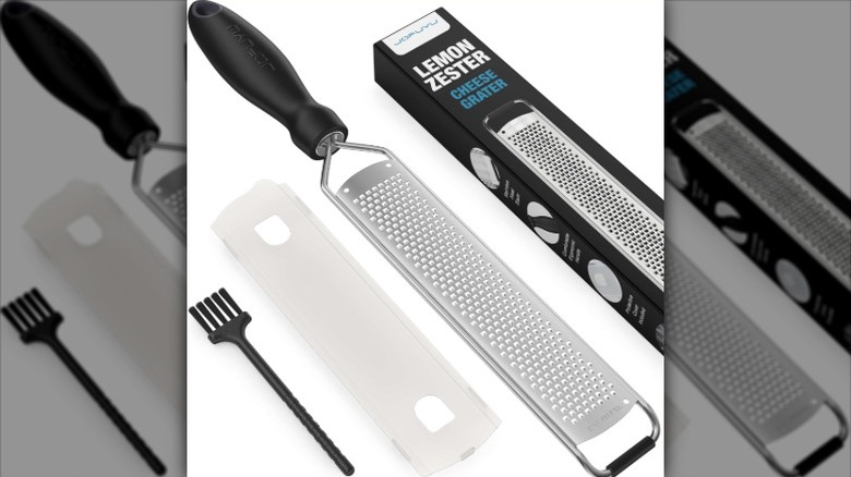 A lemon zester next to a box, cleaning brush, and cover