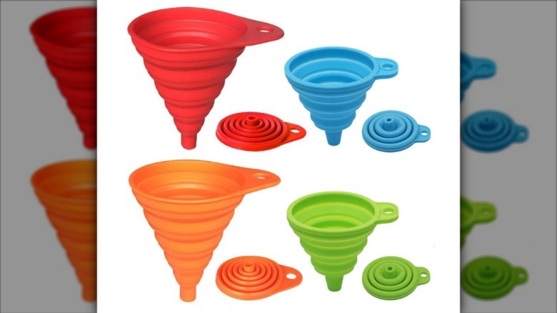 Four collapsible kitchen funnels in various colors against a white background