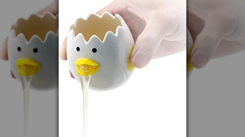 Close up image of person pouring the LuoCoCo Vomiting Chicken Egg Separator with egg white coming from its mouth