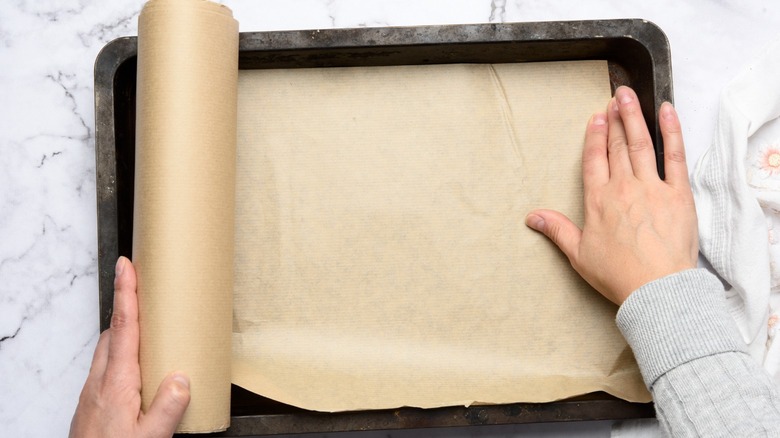 Hands rolling out parchment paper