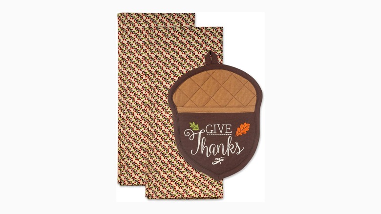 Two red and green patterned dish towels and an acorn-shaped heat matt on a white background