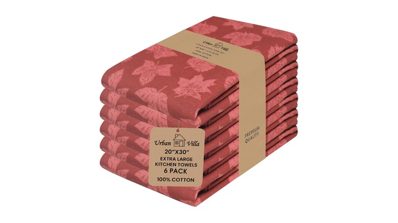 A package of six red kitchen towels with a leaf pattern in a lighter pink and red