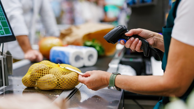 A supermarket cashier scans a bag of potatoes