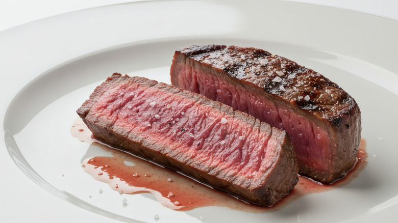 A medium-rare steak sitting on a white plate
