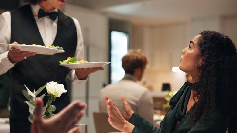 An annoyed customer speaks to a server in a restaurant