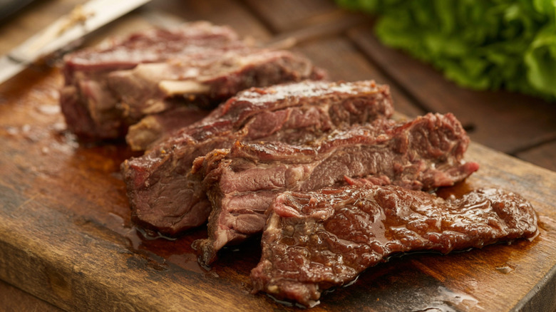 A well-done skirt steak, sliced on a cutting board