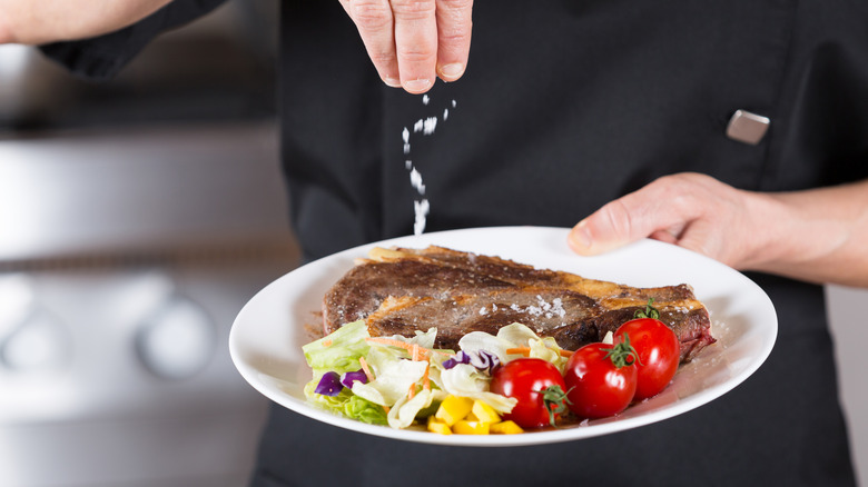 Chef sprinkling salt on food