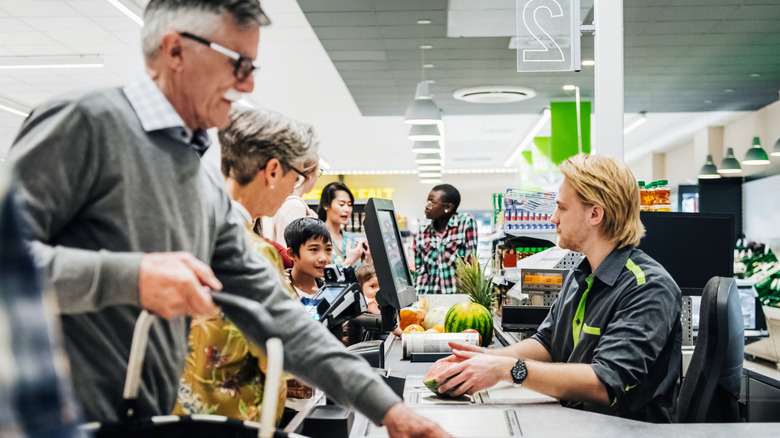 Several people standing in a line at a grocery store checkout