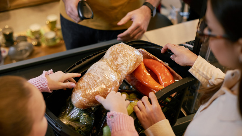 Shoppers have placed a basket full of groceries on the conveyor belt during checkout