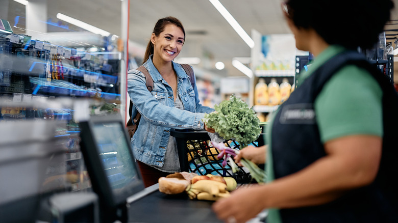 A woman smiling at a cashier during checkout at a grocery store