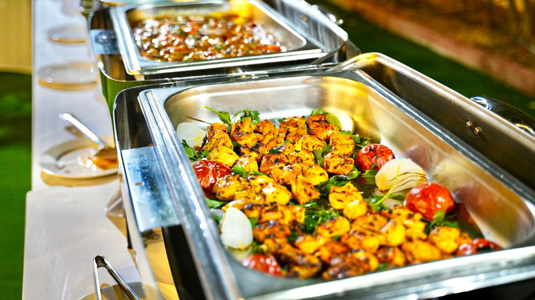 Buffet trays with chicken, onions, and tomatoes