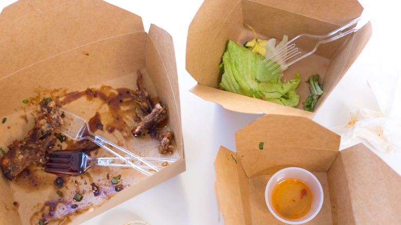 Three brown to go containers with food leftovers