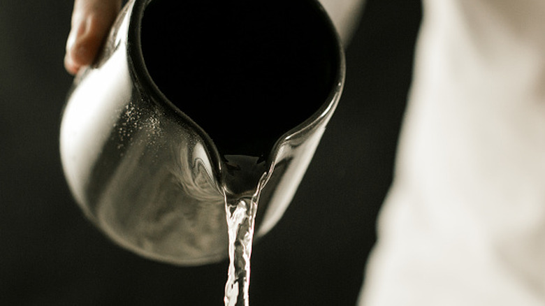 A close up of water pouring from a metal jug
