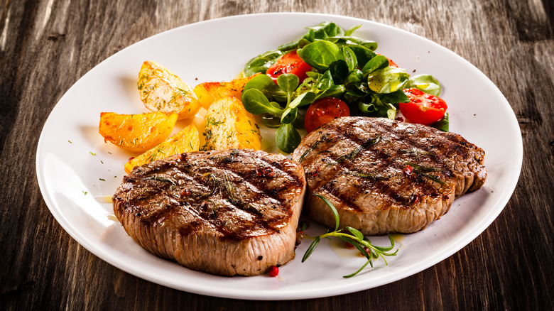 Steaks served on a plate with potatoes and salad
