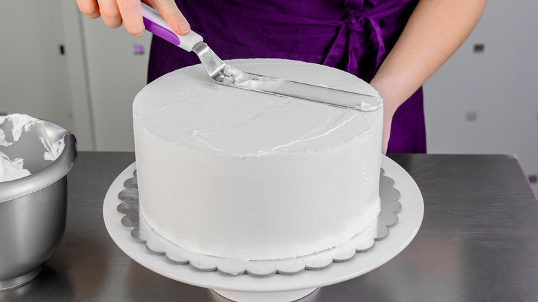 woman putting whipped topping on cake