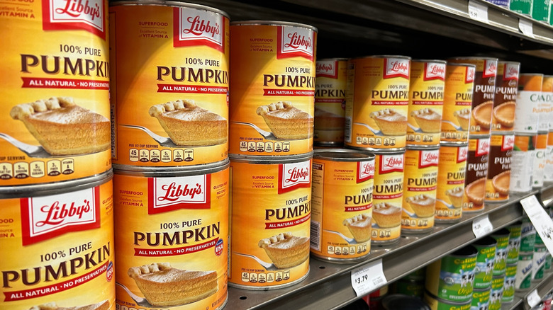 A grocery shelf lined with cans of pumpkin purée