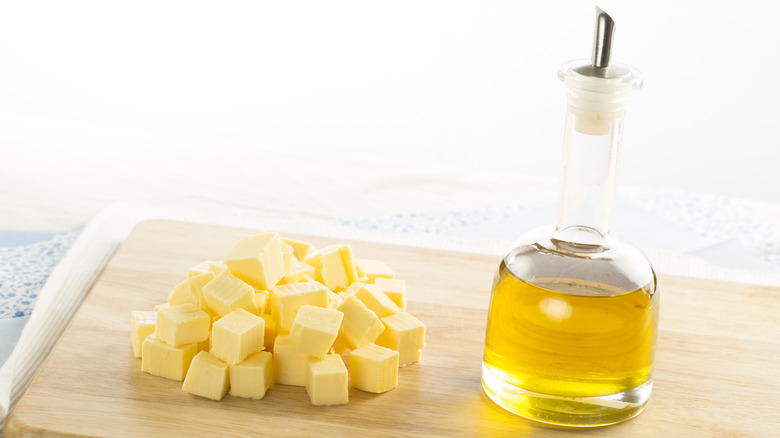 Butter cut into cubes next to a bottle of cooking oil