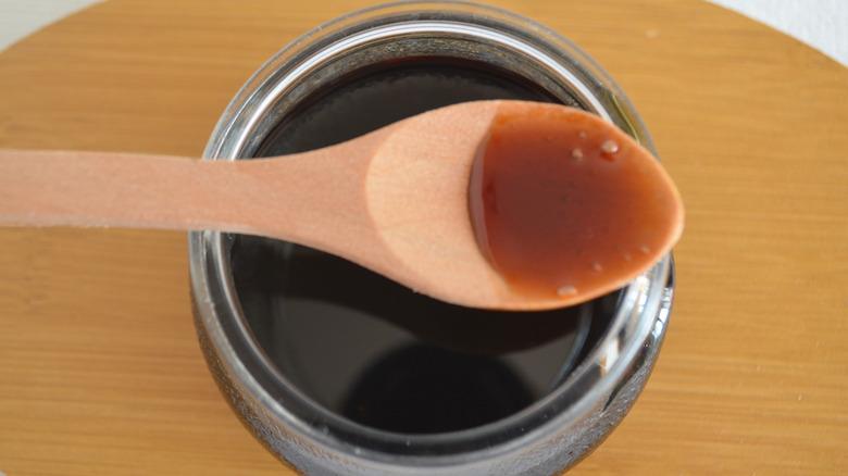 Close up of a jar of molasses with a wooden spoon on top
