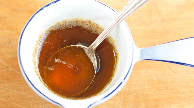 Close up of brown butter inside a white container with a silver spoon inside
