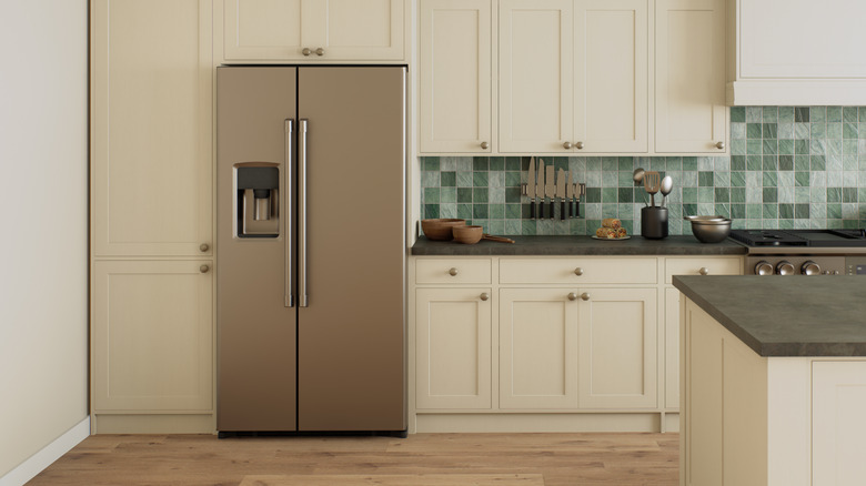 Close up of a silver refrigerator sat into cream cabinets