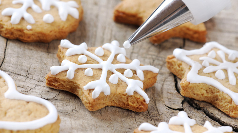 A star shaped cookie is being iced in white