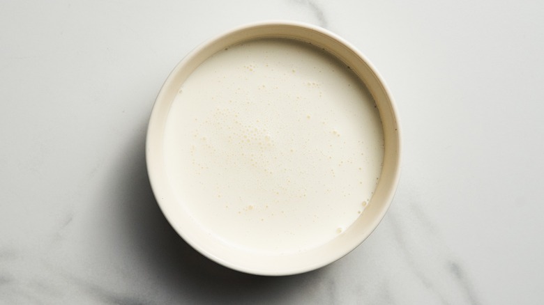 Close-up of a bowl of heavy cream against a white marbled surface