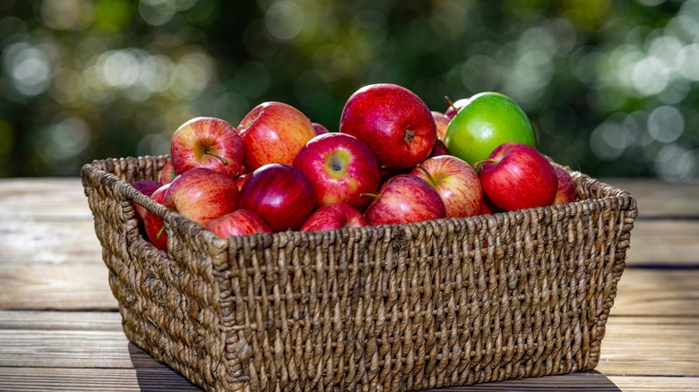 A wicker basket with fresh red apples against a blurred background