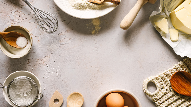 Several baking ingredients are arranged on a concrete surface