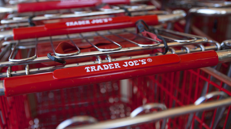 Close up of a red Trader Joe's cart with the text "Trader Joes" on it.