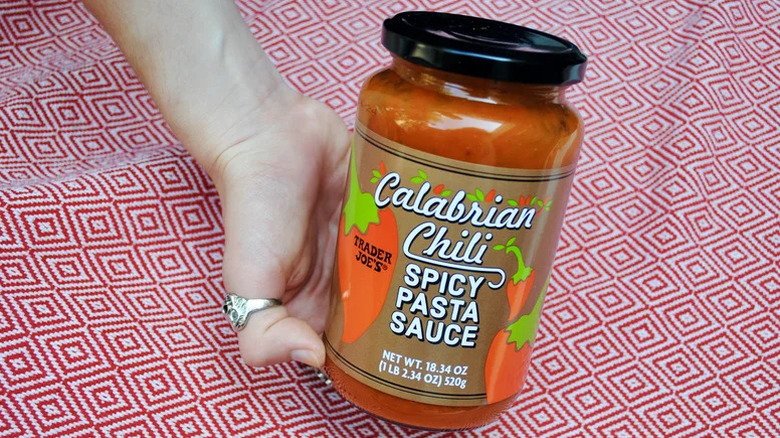 Jar of Trader Joes Calabrian chili spicy pasta sauce held over a red clothe