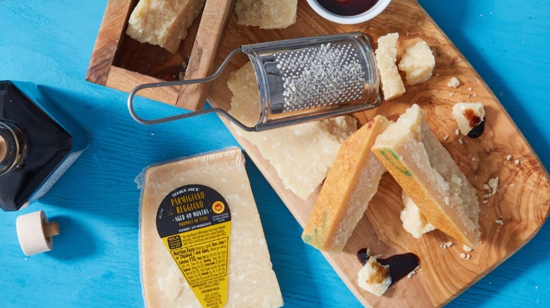 Trader Joes aged Parmigiano Reggiano with a cheese board, grater and pieces of cheese