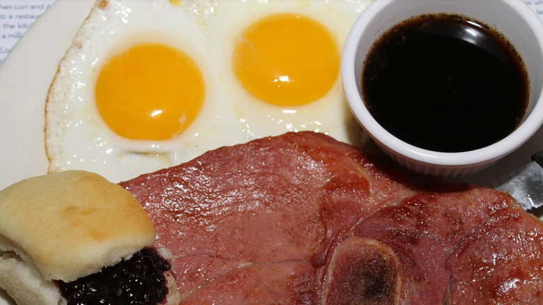 Ham, Red Eye Gravy, biscuits, and fried eggs on a white plate