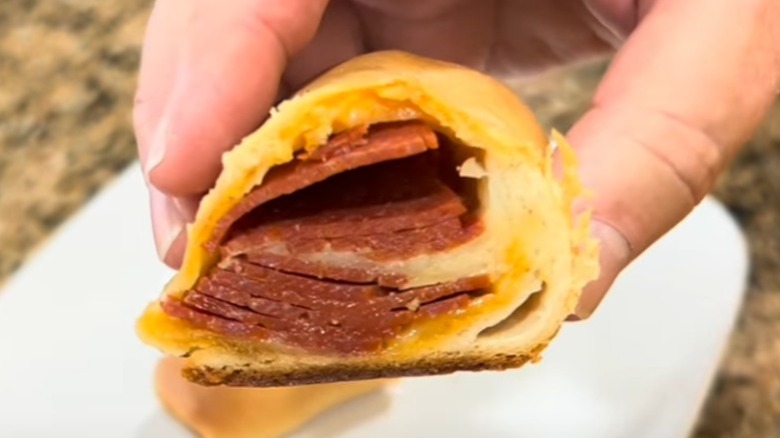 A person holding half a pepperoni roll