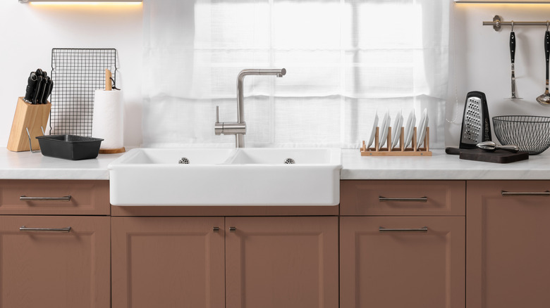 Kitchen counter with white sink and mocha mousse painted cabinetry below