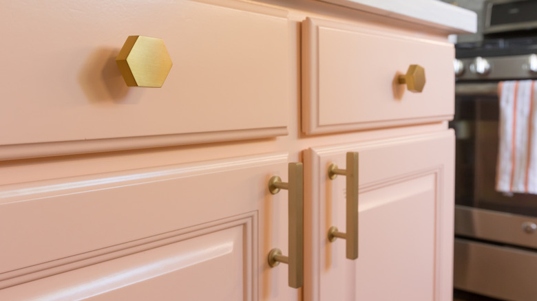 Modern kitchen featuring pink peach cabinets with gold hardware