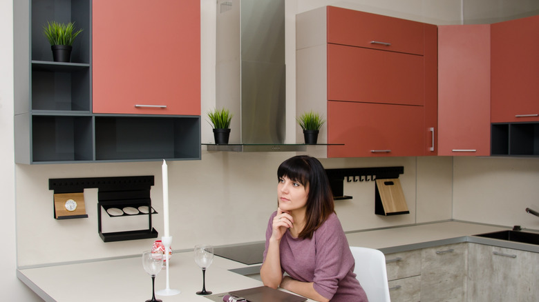 Person sits in kitchen with pinkish-brown cupboards