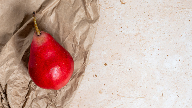 a bright red starkrimson pear on crumpled natural paper against a neutral background