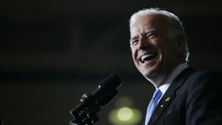 Joe Biden laughs in front of a microphone