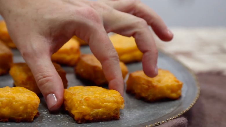 A hand picks up a cheese dream from a platter