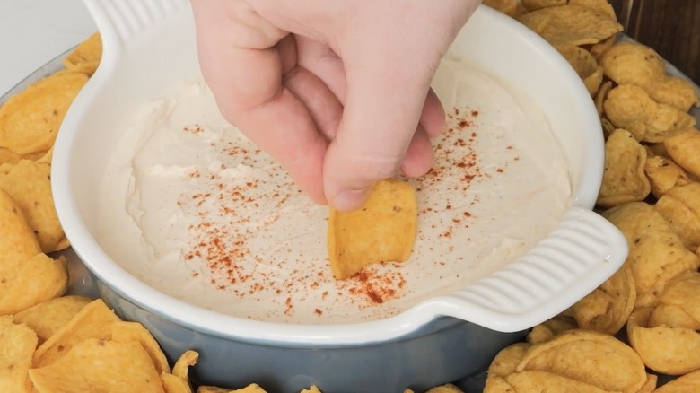 A hand dips a chip into Philly Hostess dip