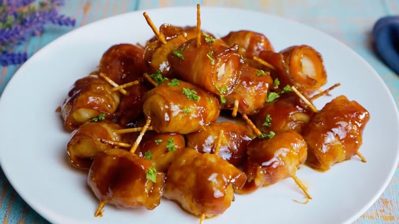 Bacon-wrapped rumaki on cocktail sticks, covered in sauce