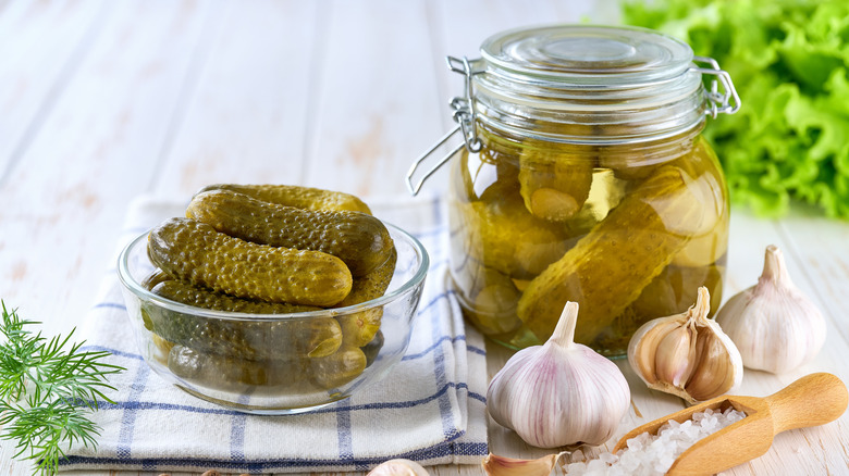 Canned pickled cucumbers, with a bowl of cucumbers next to it
