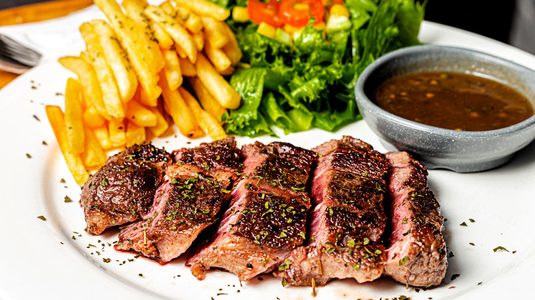 Sliced steak with fries and salad